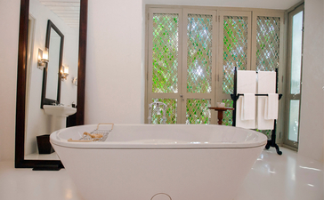 Bathroom at Amangalla with freestanding bath positioned beneath a window overlooking the garden.