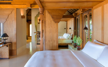 Amankila resort's Garden Suite bedroom with warm wood interiors, flowing layout, and garden views.