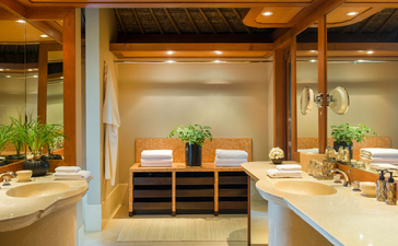 Indrakila Suite bathroom at Amankila resort with dual vanities, stone counters, and central wooden shelving, Bali.