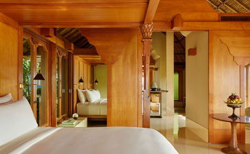 Indrakila Suite bedroom with warm timber finishes and open-plan layout at Amankila resort, Bali.