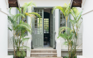 Khan Pool Suite entrance at Amantaka, framed by potted palms and architectural symmetry.