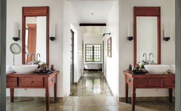 Khan Pool Suite bathroom at Amantaka, Laos, featuring dual vanities with wooden cabinetry and mirrors.