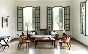 Khan Pool Suite sitting area at Amantaka, Laos, with wooden furniture and latticed screens.