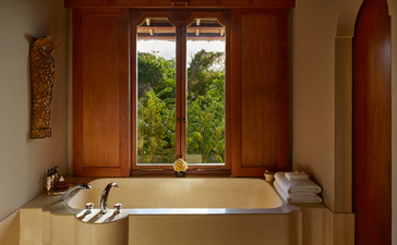 Baignoire encastrée avec portes coulissantes en bois dans la suite Kilasari à Amankila, resort à Bali.