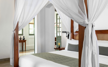 Mekong Pool Suite bathroom at Amantaka with four-poster bath and sheer white drapes.