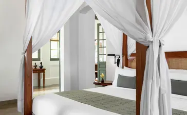 Mekong Pool Suite bathroom at Amantaka with four-poster bath and sheer white drapes.