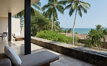 Ocean Hill Pool Suite balcony with daybed overlooking palm trees and coastline at Amanwella, Sri Lanka.