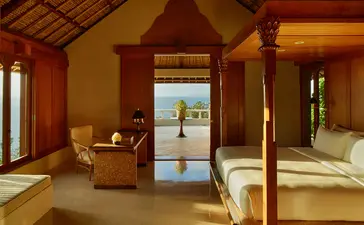 Chambre spacieuse avec lit à baldaquin, mobilier en bois et vue sur l'océan à Amankila, Bali.