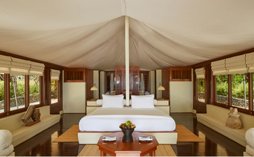 Ocean Tent bedroom at Amanwana with draped canvas ceiling and wooden furnishings overlooking Indonesian landscape.