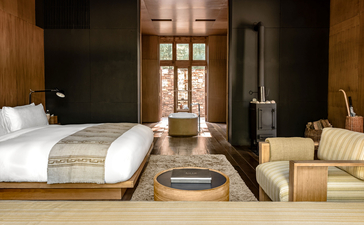 Principal bedroom at Amankora with wooden walls, cream bedding, and traditional Bhutanese architectural details.