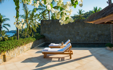 アマンキラ リゾートのプール スイート、バリ島インドネシア。デッキ チェアが置かれたテラスから海が見える。