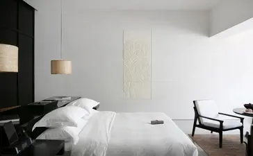 Principal bedroom with pool suite view at Amansara, Cambodia, featuring minimalist décor and black accent wall.