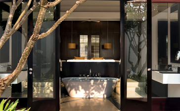 Pool suite pavilion at Amansara with dark timber detailing and illuminated interior seating area, Cambodia.