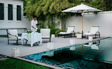Pool Suite at Amantaka with loungers, umbrellas and verdant gardens overlooking the water.