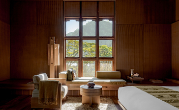 Wooden bathroom at Amankora with large window overlooking landscape and freestanding bathtub.