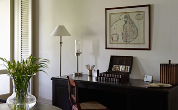 Verandah Chamber at Amangalla with dark desk, floor lamp, and botanical artwork.