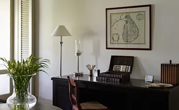 Verandah Chamber at Amangalla with dark desk, floor lamp, and botanical artwork.