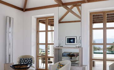 安缦卓熠度假村一卧室别墅的宽敞起居室,配有木梁天花板、双门和现代壁炉。