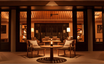Three-bedroom residence at Amanoi with illuminated wooden pavilion and seated seating area at dusk, Vietnam.