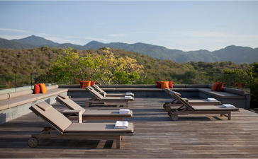 Three-bedroom residence at Amanoi with sunloungers on a wooden deck overlooking forested mountains in Vietnam.
