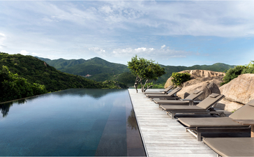 Amanoi resort five-bedroom residence with wooden deck overlooking calm river and forested hills.