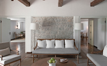 Adriatic Suite at Aman Sveti Stefan, Montenegro, featuring a principal bedroom with stone feature wall and modern furnishings.