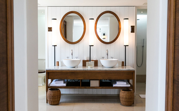 Adriatic Suite bathroom at Aman Sveti Stefan with dual circular mirrors and wooden vanity.