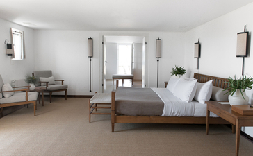 Principal bedroom at Aman Sveti Stefan with bed, seating area and doors opening to terrace.