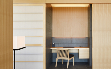Aman Tokyo suite with wooden sliding doors opening onto a seating area with blue accent wall.