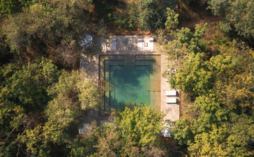 Aerial view of Aman-i-Khas nestled amongst dense forest with a turquoise plunge pool and surrounding pathways.