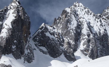 Snow-covered mountain peaks at Amandayan beneath a dramatic sky.