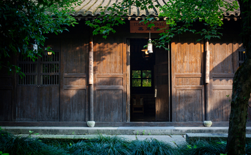 Wooden doors and windows of a dining pavilion at Amanfayun, with verdant vines cascading above.