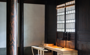 Simple wooden desk and chair beside a latticed window at Amanfayun.