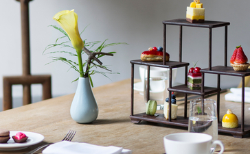 Wooden desk at Amanfayun with yellow flowers, open notebook, and decorative shelving unit.