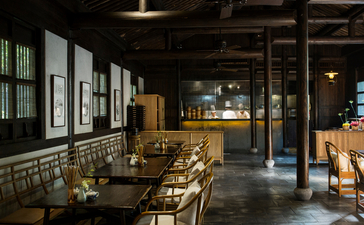 Amanfayun's dining venue with wooden tables and chairs, framed artworks on walls, and warm overhead lighting.