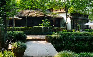 Courtyard at Amanfayun with manicured hedges and traditional architecture framed by mature trees.