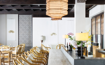 Dining area at Amanfayun with wooden chairs, long table, and pendant lighting beneath exposed beams.
