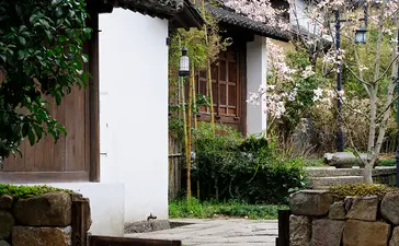 Stone gateway with wooden door leading to Amanfayun courtyard, ivy-clad walls beyond.