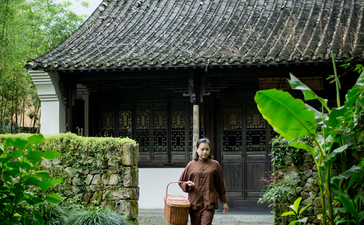 A woman walks through a traditional pavilion surrounded by lush greenery at Amanfayun.