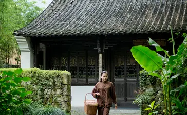A woman walks through a traditional pavilion surrounded by lush greenery at Amanfayun.