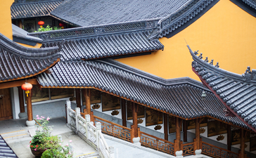 Amanfayun's traditional curved rooflines with yellow walls and manicured gardens nestled among green hillside vegetation.