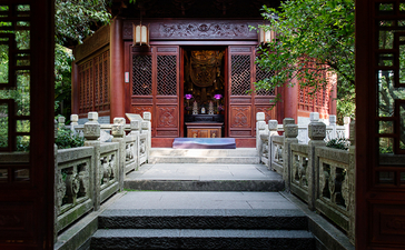 Stone steps lead through a red wooden doorway framed by ivy-covered walls at Amanfayun.