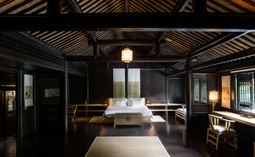 Amanfayun bedroom with dark timber ceiling, central bed, and warm pendant lighting.