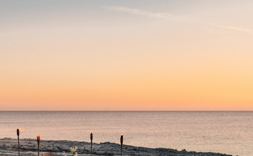 Sunset view over a serene beach with wooden loungers at Amanyara resort.