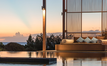 Pavilion with timber frame overlooking still water at sunset, Amanyara resort.
