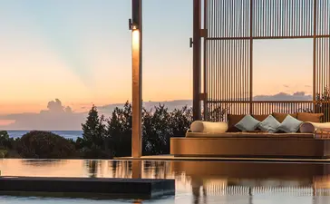 Pavilion with timber frame overlooking still water at sunset, Amanyara resort.