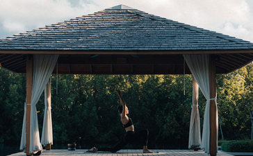 Pavilion with peaked roof reflected in still water at Amanyara resort.