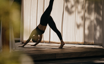 Silhouette d'une personne en posture de yoga inversée près d'une piscine à Amanyara resort.