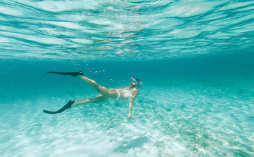 Un invité en train de faire de la plongée en apnée dans les eaux turquoise cristallines d'Amanyara.