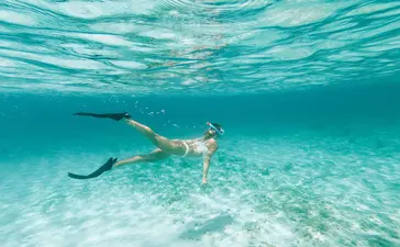 Un invité en train de faire de la plongée en apnée dans les eaux turquoise cristallines d'Amanyara.